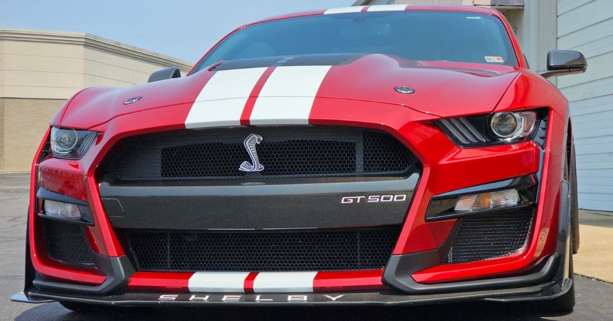 Red Ford Mustang GT500 with a glossy ceramic coating finish parked outdoors, showcasing a pristine s