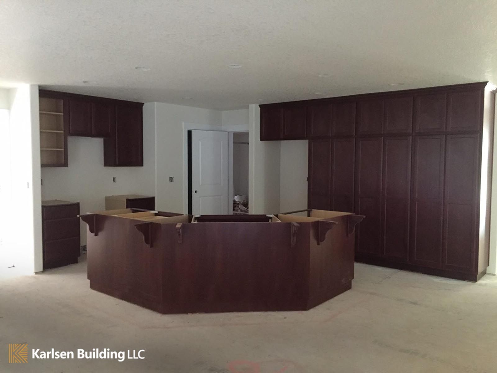 Kitchen with dark brown cabinets, an island, and white walls, under construction.