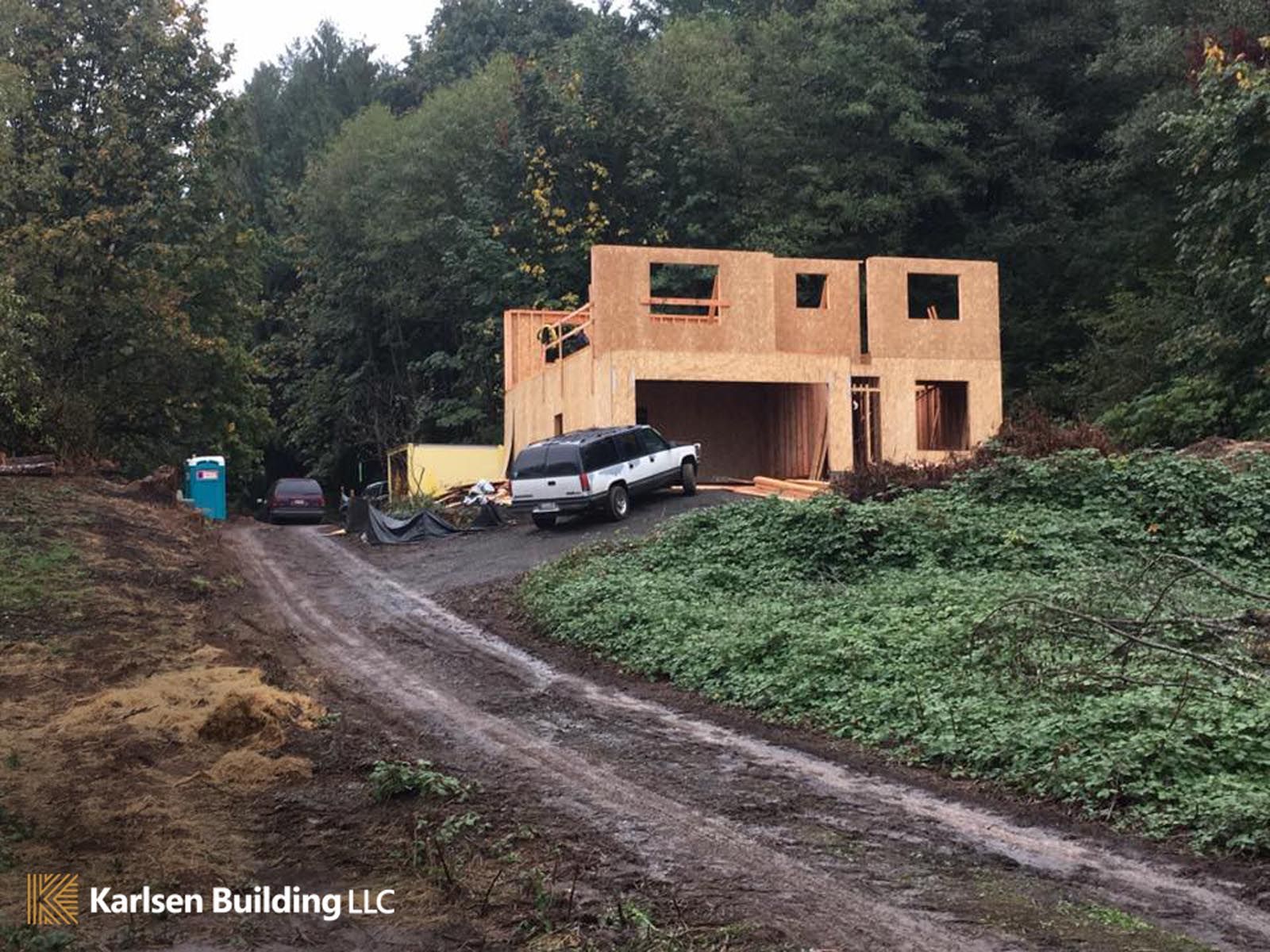 A car is parked in front of a house that is being built by karlson building llc