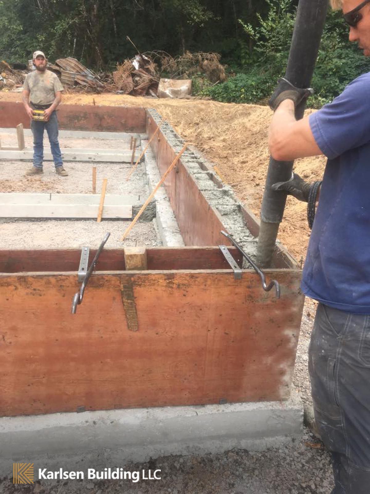 A man is pouring concrete into a wooden box.