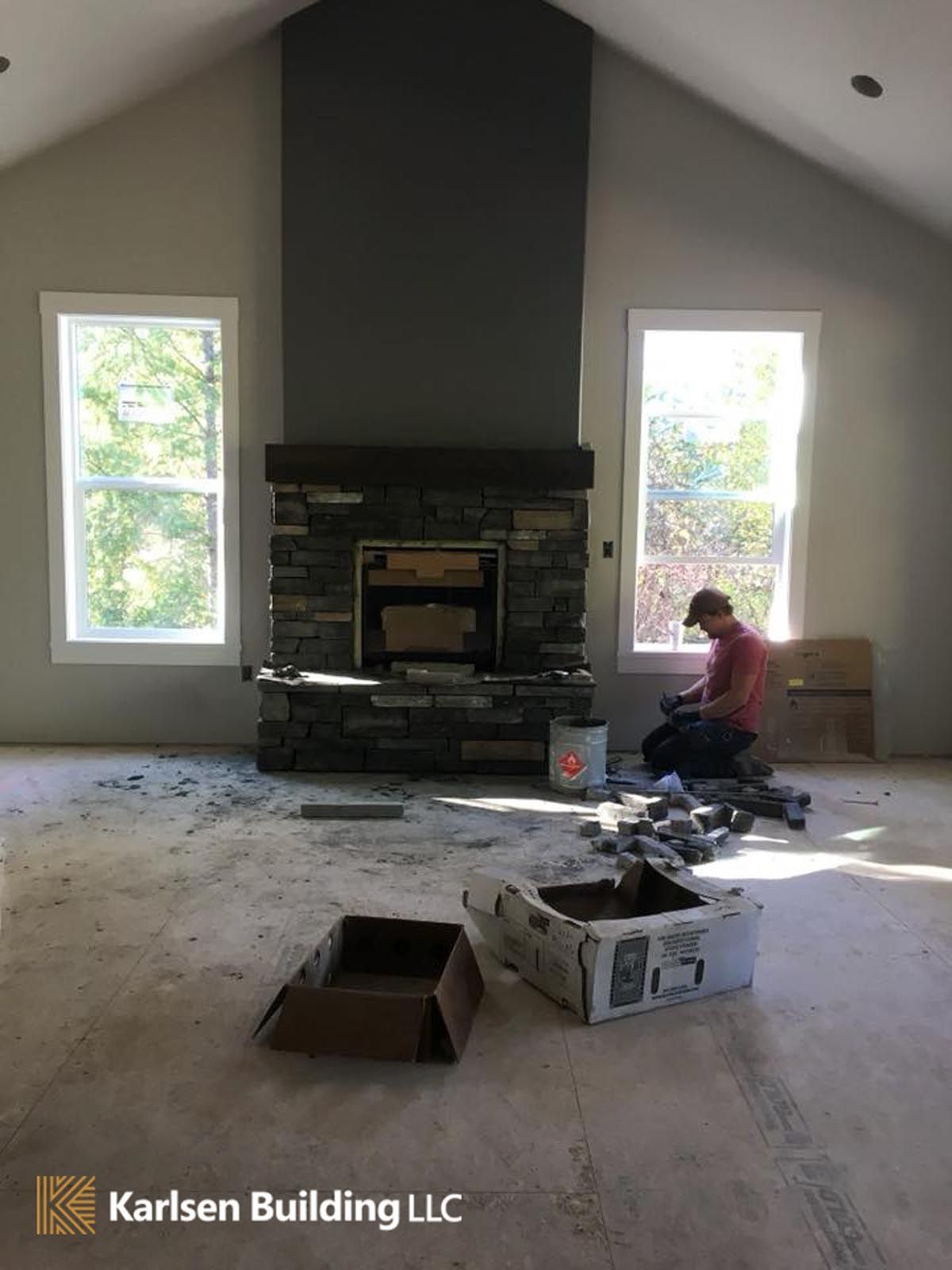 A man is working on a fireplace in a living room.