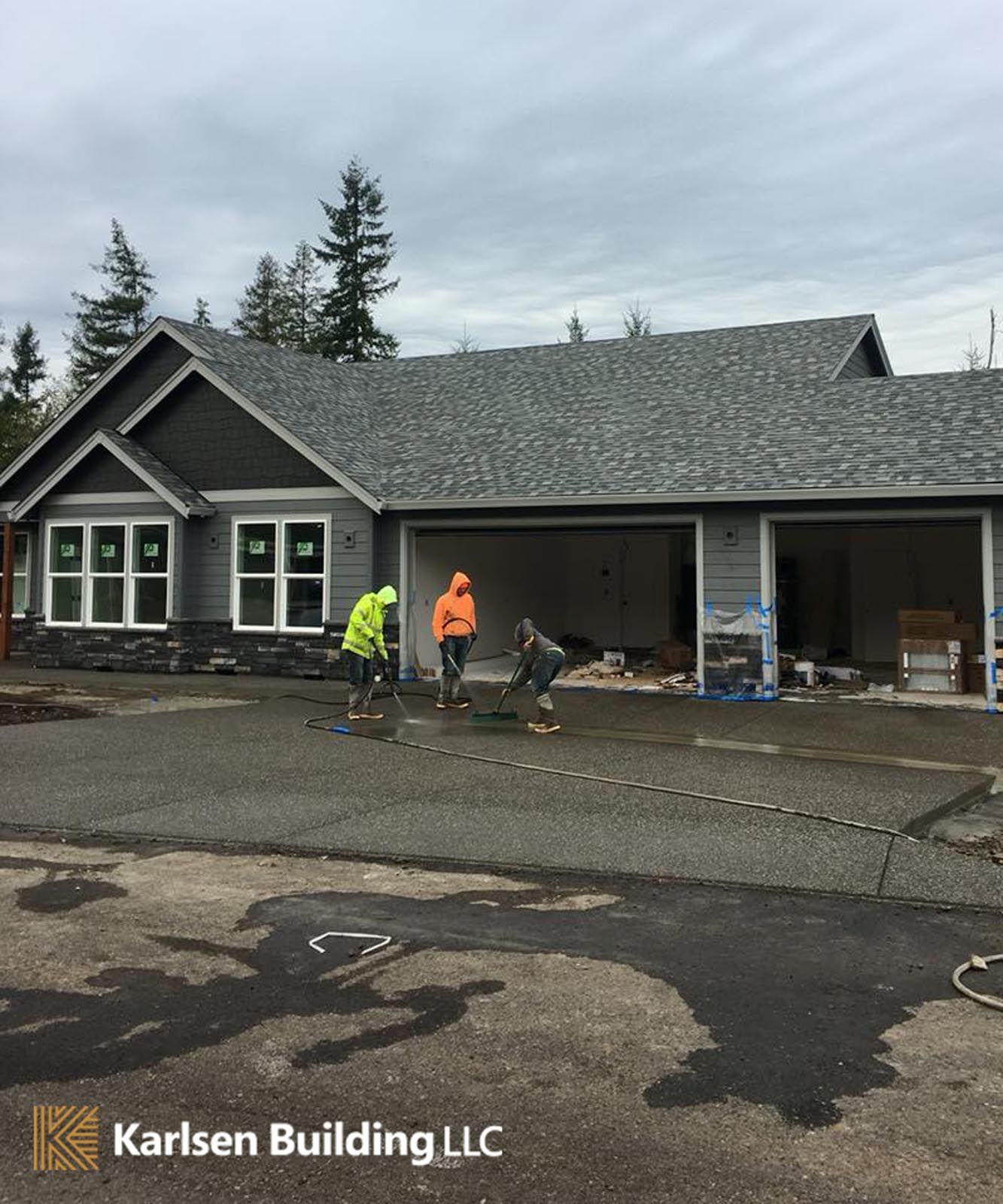 A group of people are working on a driveway in front of a house.