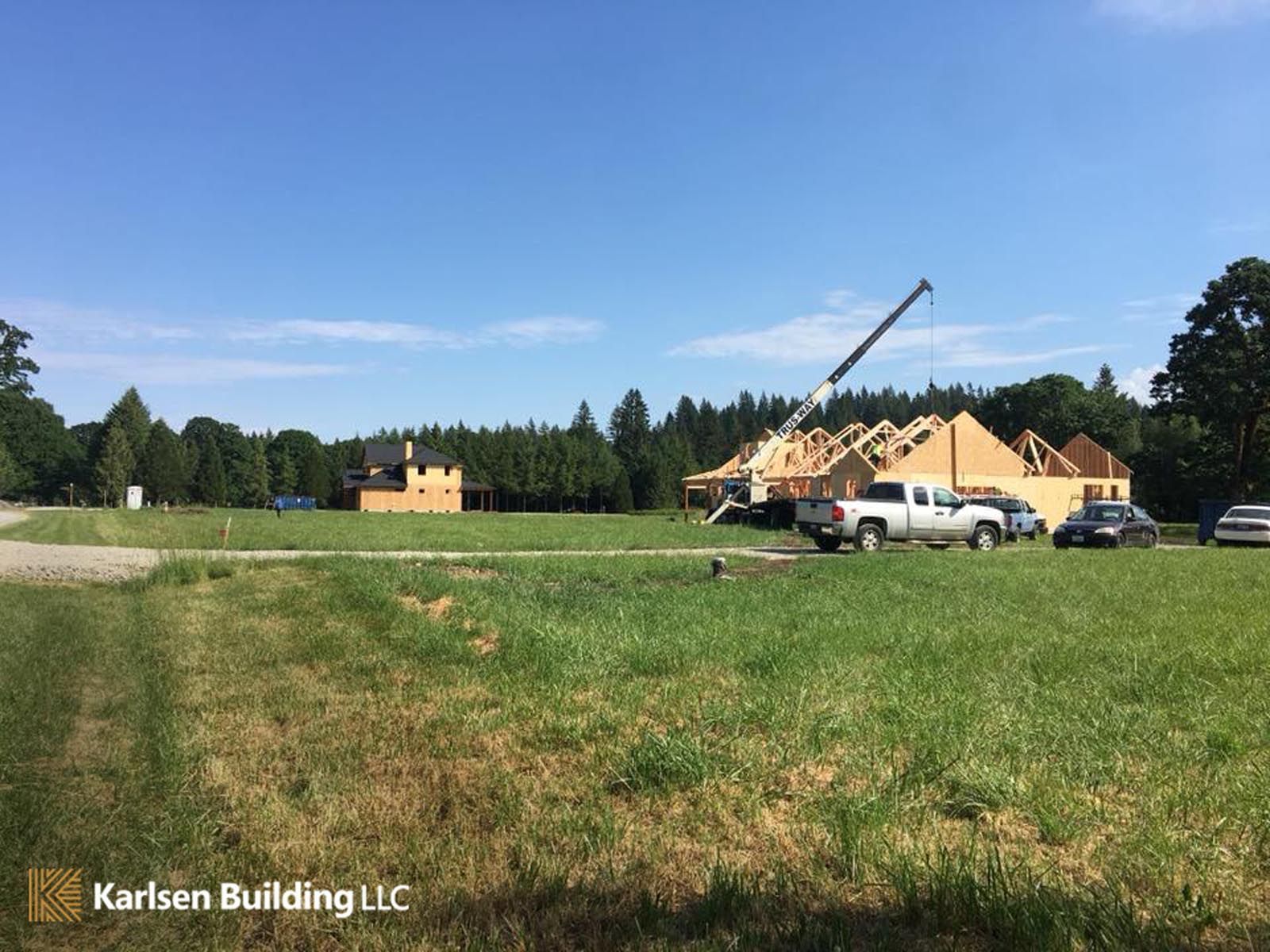 A crane is being used to build a house in a grassy field.