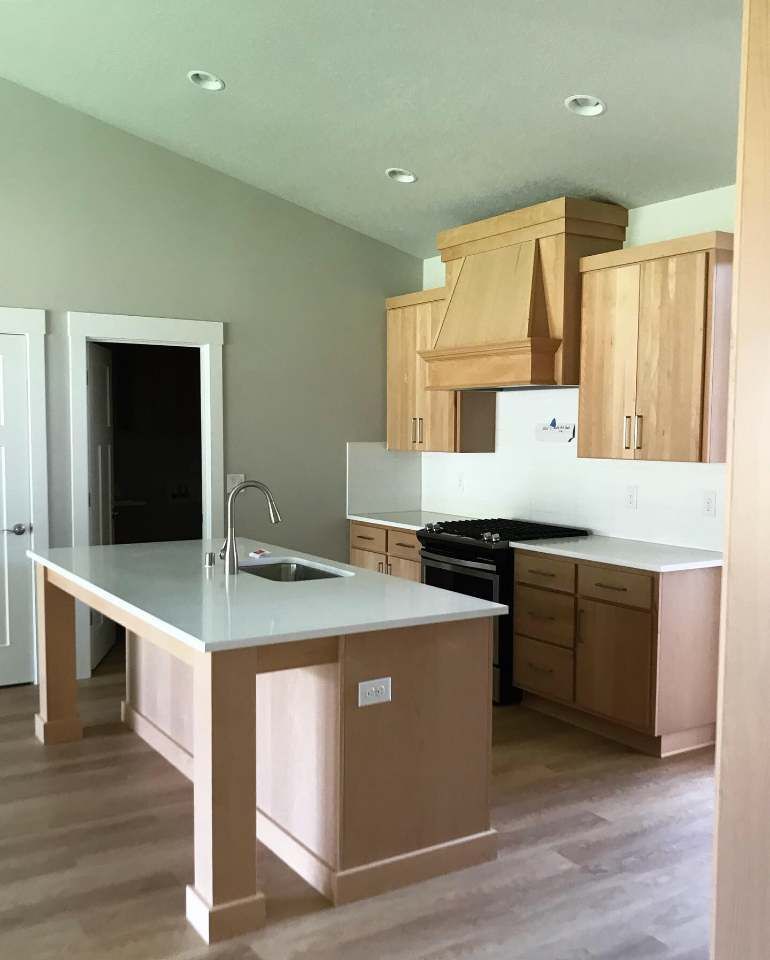 A kitchen with wooden cabinets and a large island in the middle