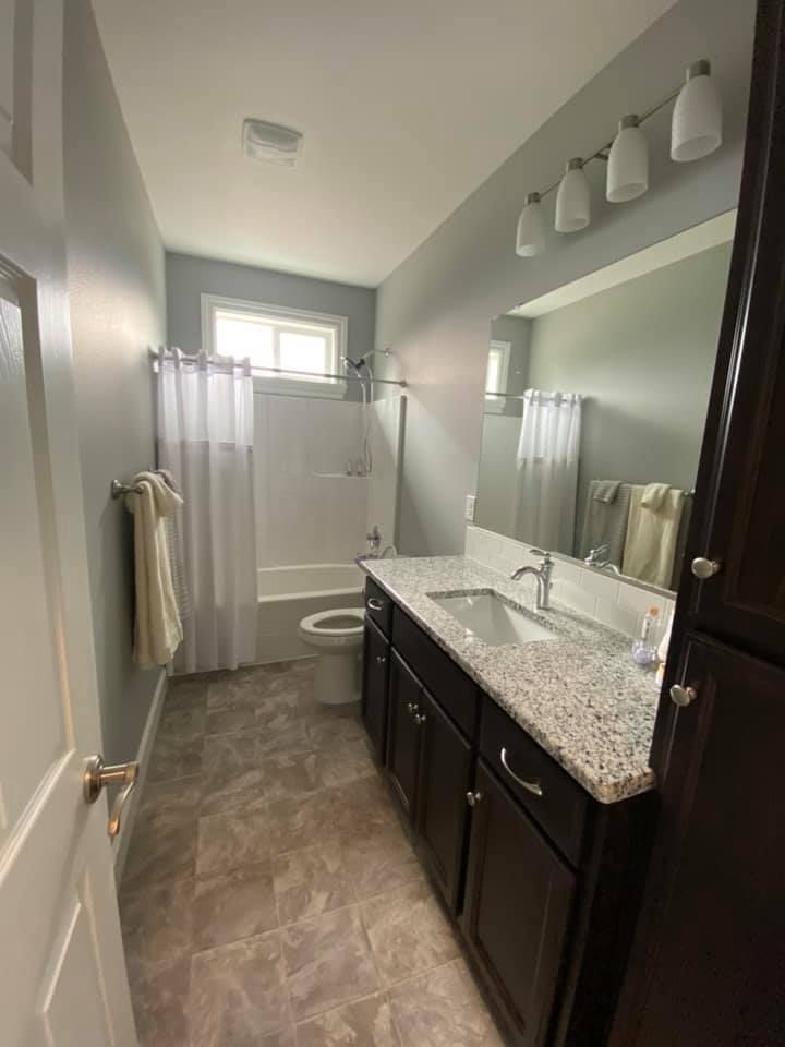 A bathroom with a sink , toilet , shower and mirror.