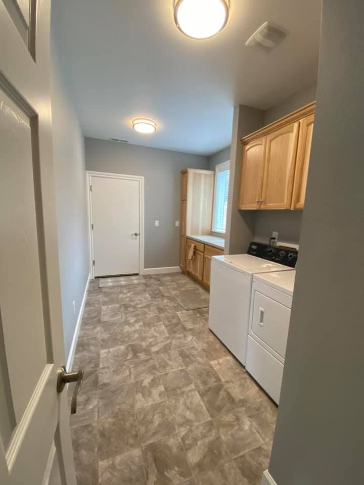 A laundry room with a washer and dryer and wooden cabinets.