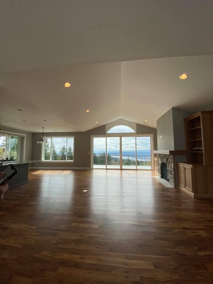 A large empty living room with hardwood floors and a fireplace.