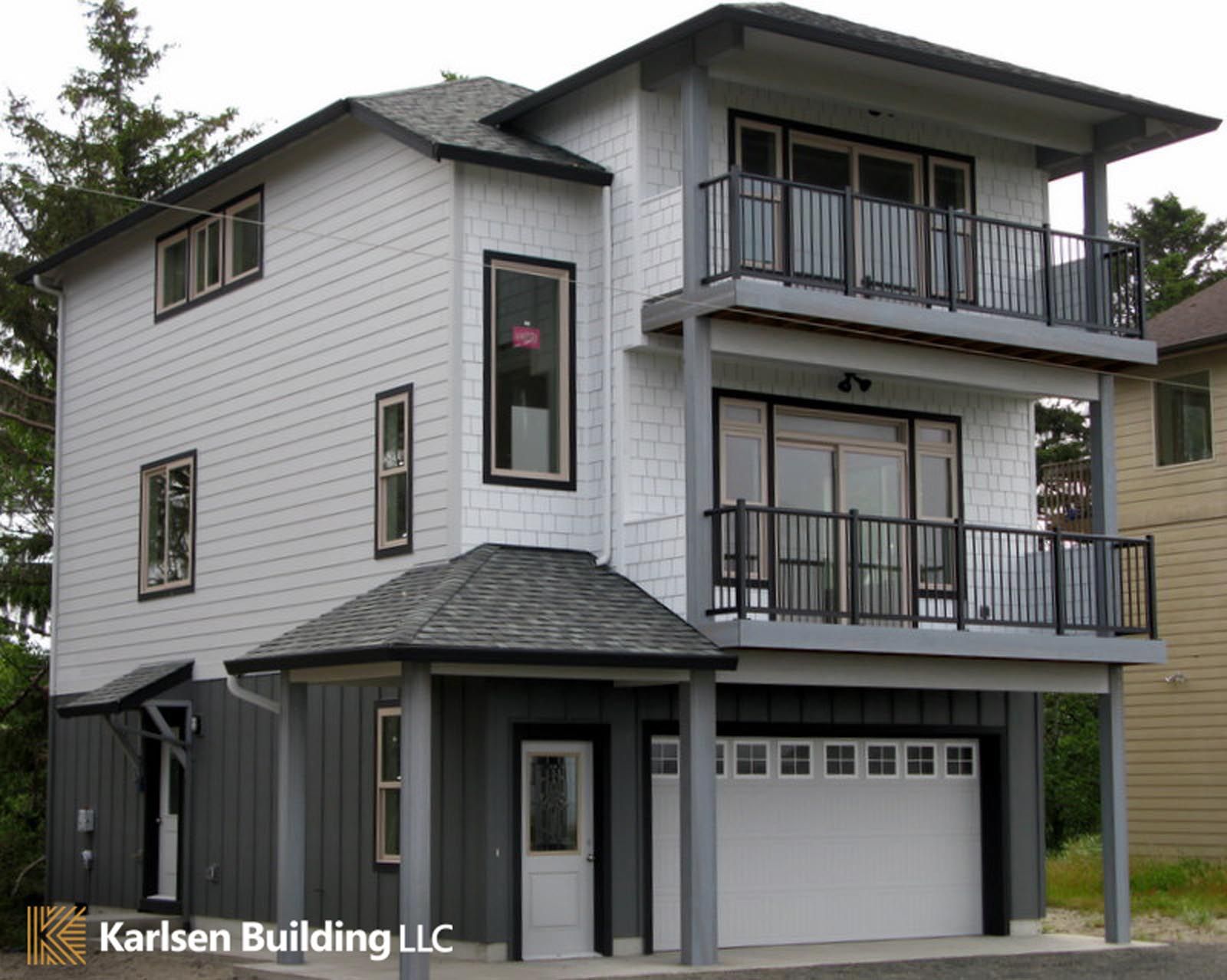 A large white house with a garage and balconies is owned by karlsen building llc