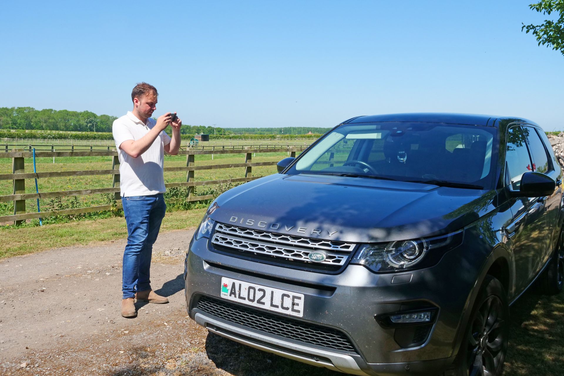 A man is taking a picture of a land rover discovery.