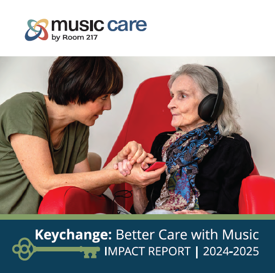 A woman wearing a mask is playing a drum for an elderly woman in a wheelchair.
