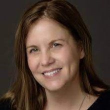 A woman with long brown hair is smiling for the camera.