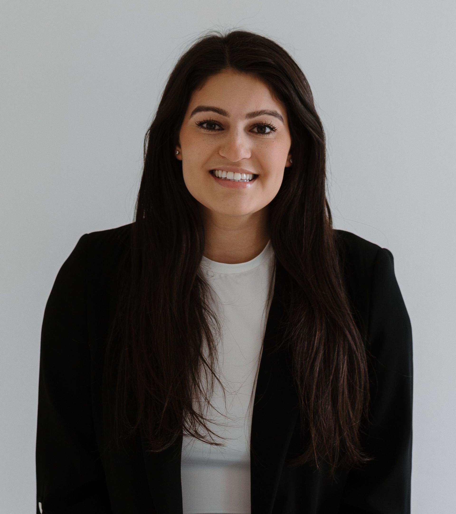 A woman wearing a white shirt and a necklace smiles for the camera.