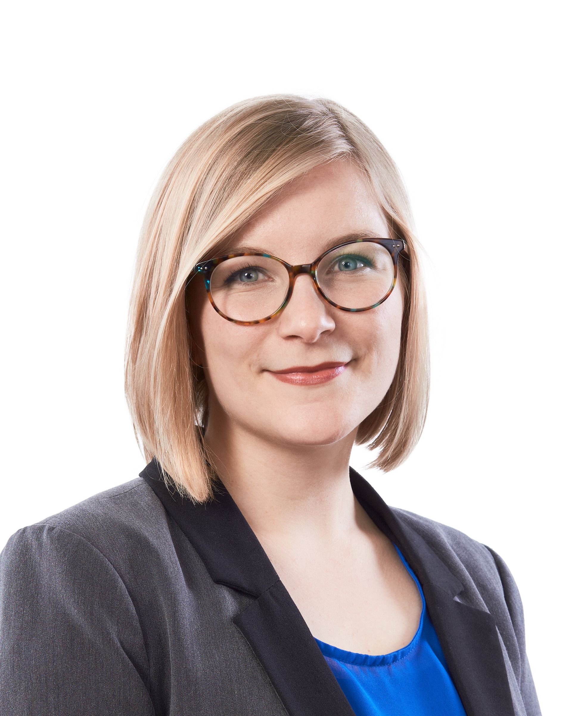 A woman wearing glasses and a blue shirt is smiling for the camera.