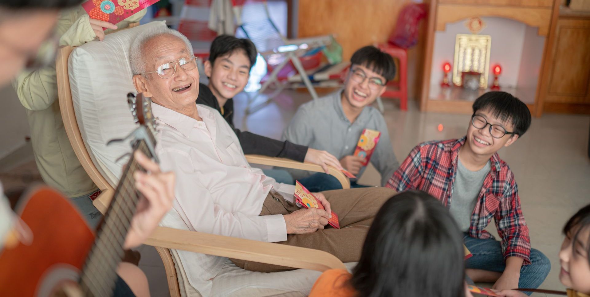 A group of people are sitting around an elderly man in a chair.