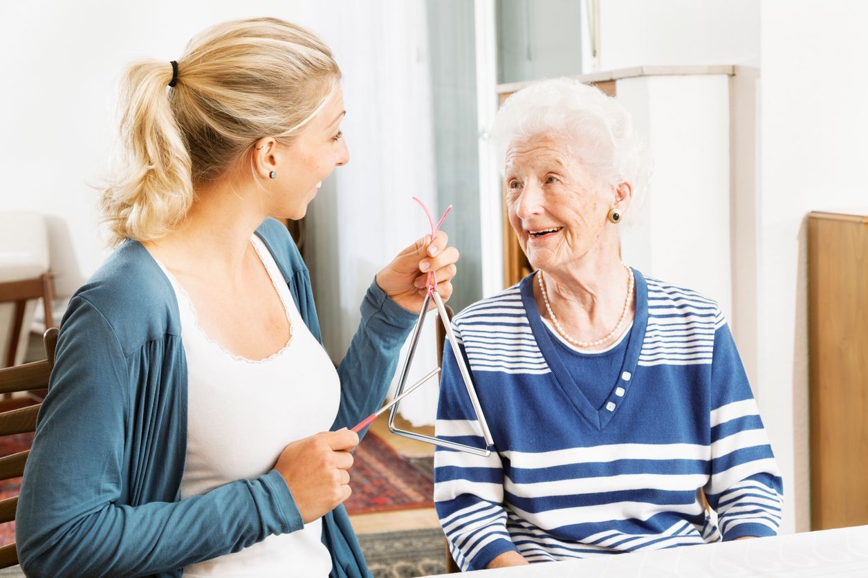 A young woman is talking to an older woman who is sitting at a table.