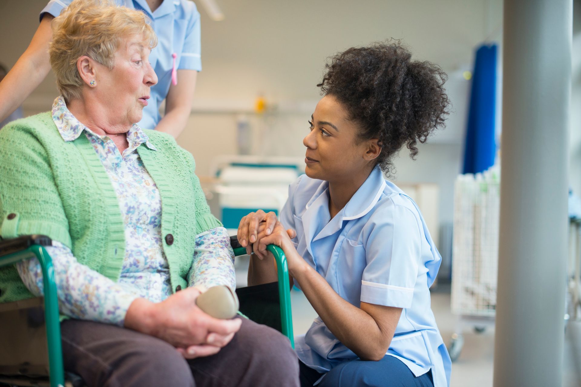 A nurse is talking to an elderly woman in a wheelchair.
