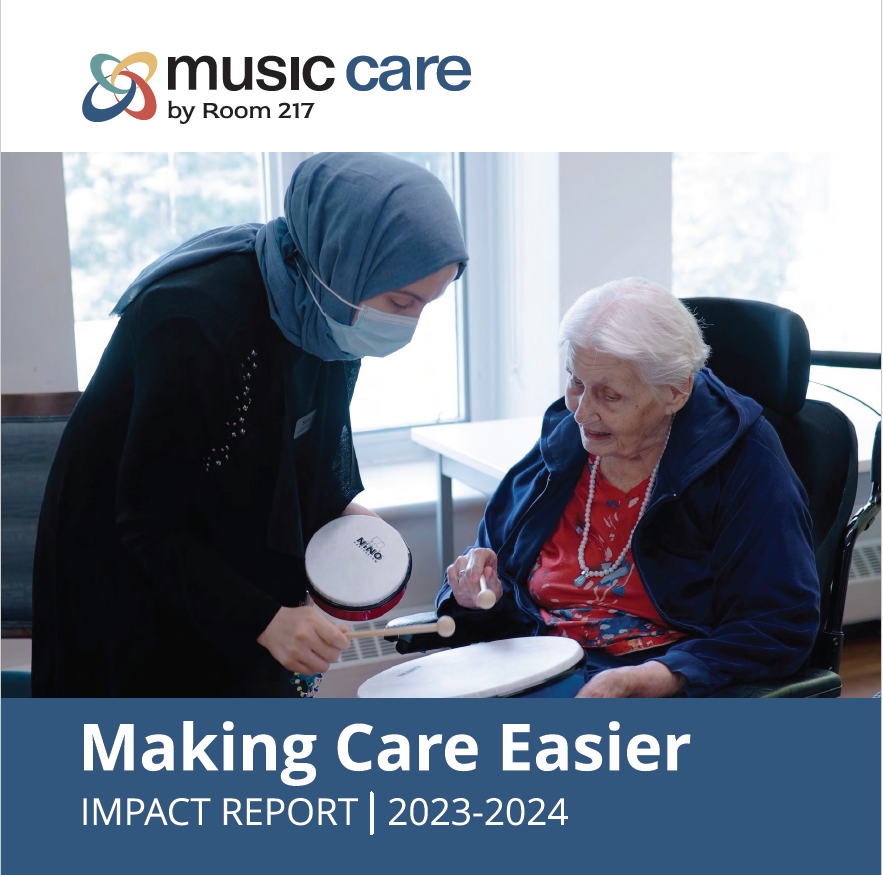 A woman wearing a mask is playing a drum for an elderly woman in a wheelchair.