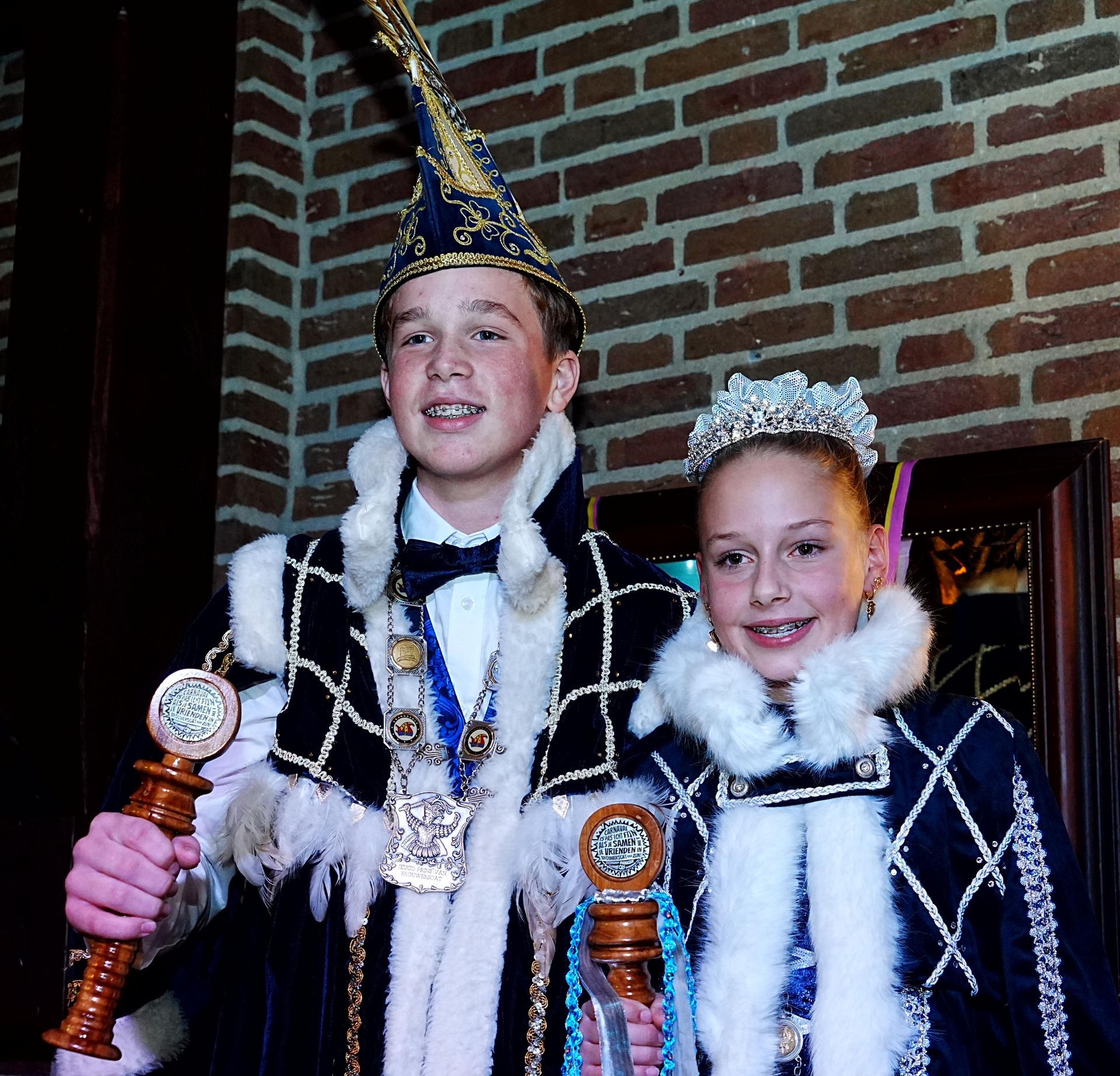 Een kantoorgang met kamers met glazen wanden, beige tapijt en twee stoelen tegenover een klein tafeltje.