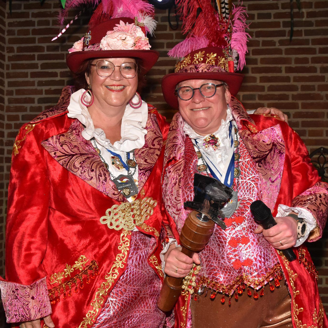 Een kantoorgang met kamers met glazen wanden, beige tapijt en twee stoelen tegenover een klein tafeltje.