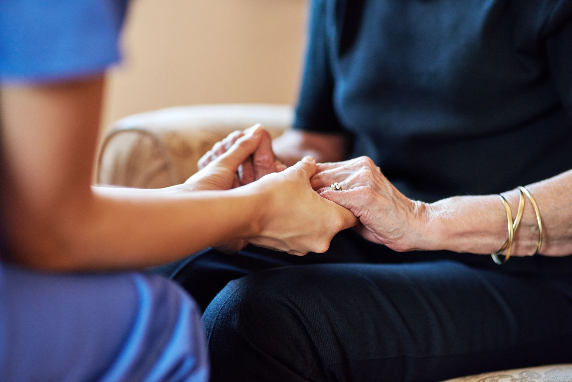 Una persona vestida con uniforme médico azul toma de la mano a otra persona, brindándole consuelo y apoyo.
