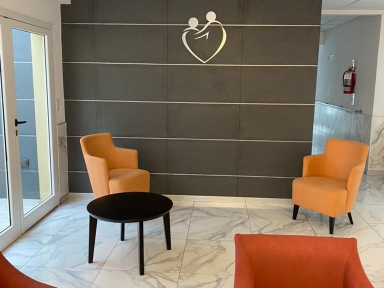 Una sala de espera con tres sillones naranjas y una pequeña mesa redonda 