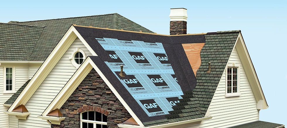 A house roof partially covered in shingles, underlayment, and roofing felt during installation.