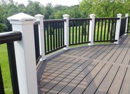 A composite deck with black railings and white posts. Green grass and trees are visible in the background.