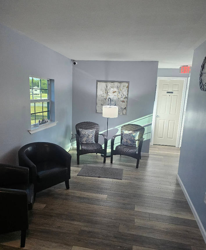 Waiting room with gray and blue walls, two patterned chairs, a black chair, and a window.
