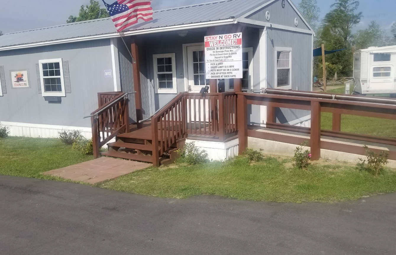 Gray building with steps, ramp, and American flag. Sign posted near the entrance.