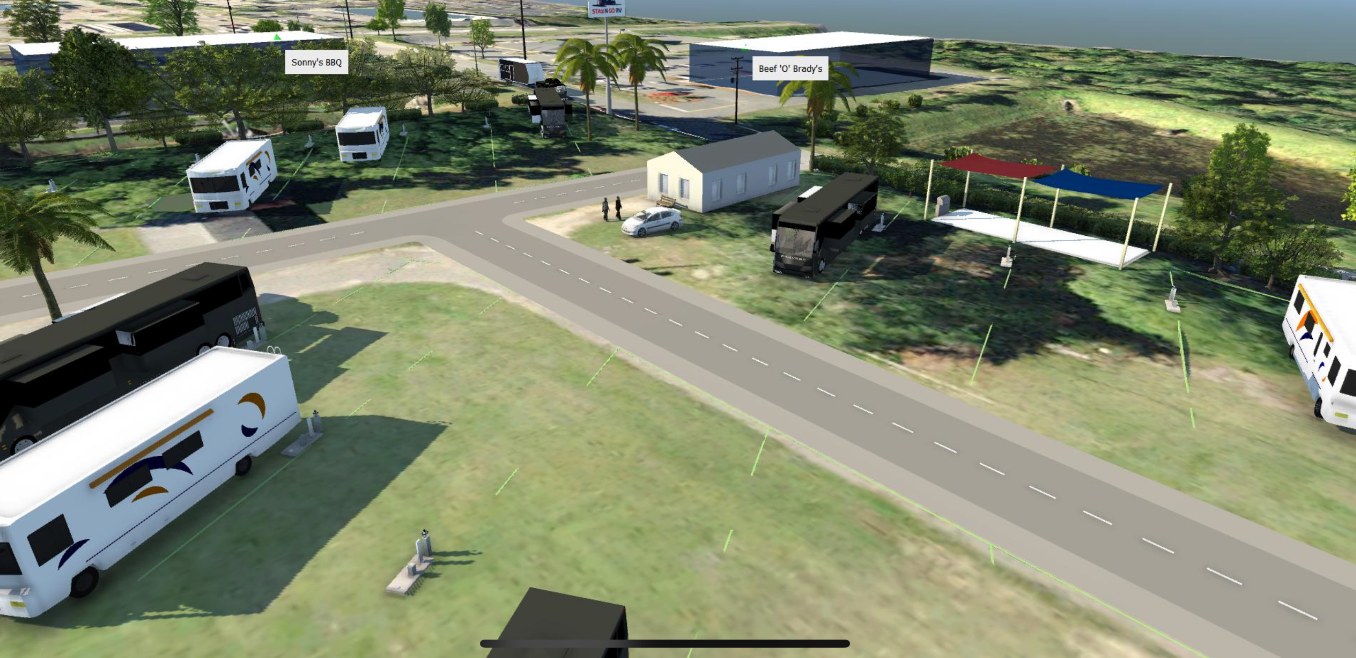 An aerial view of an RV park with parked RVs, a road, and buildings.