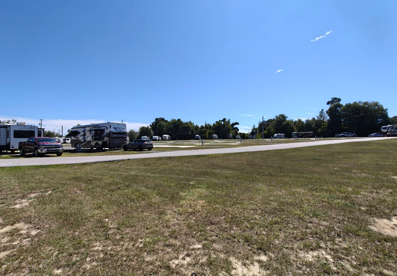 Campground with RVs parked on grass under a clear blue sky.