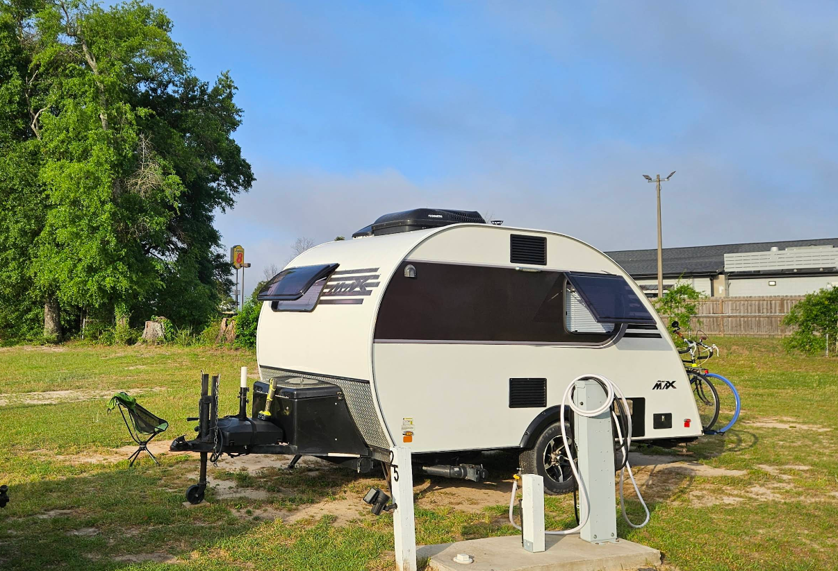 White teardrop camper trailer parked outdoors, sunny day.