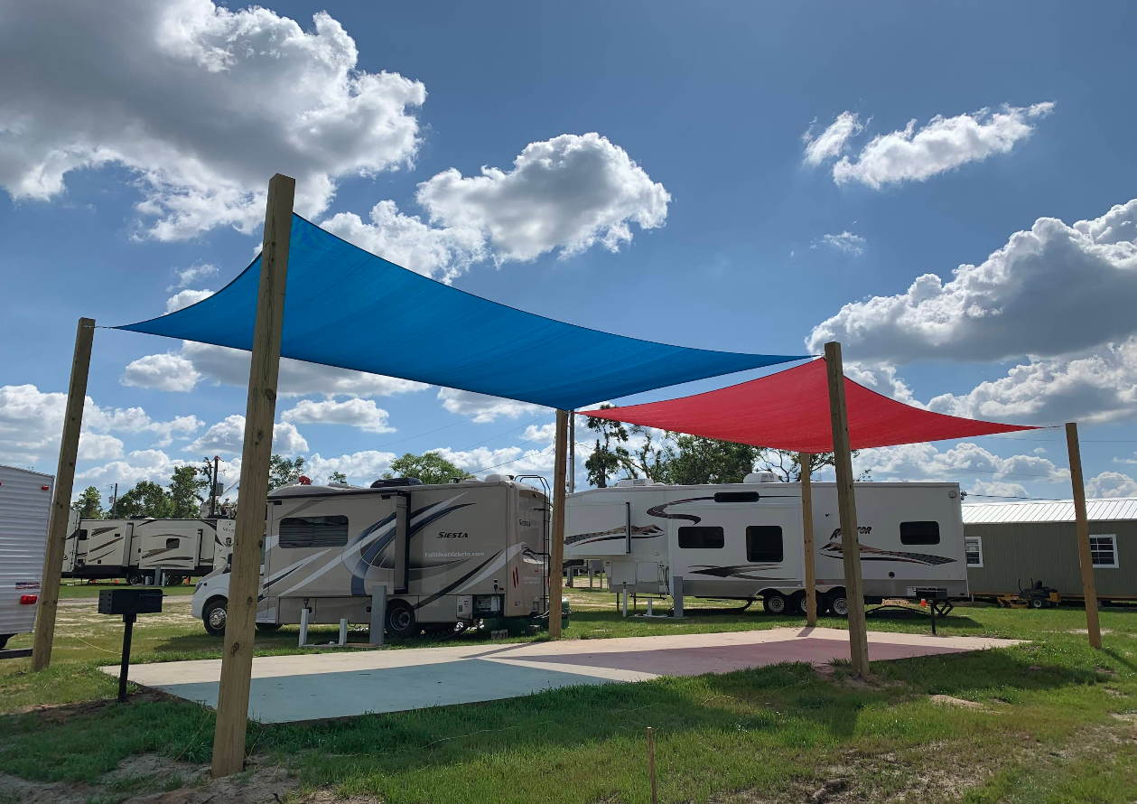RV park with blue and red shade sails; sunny day.