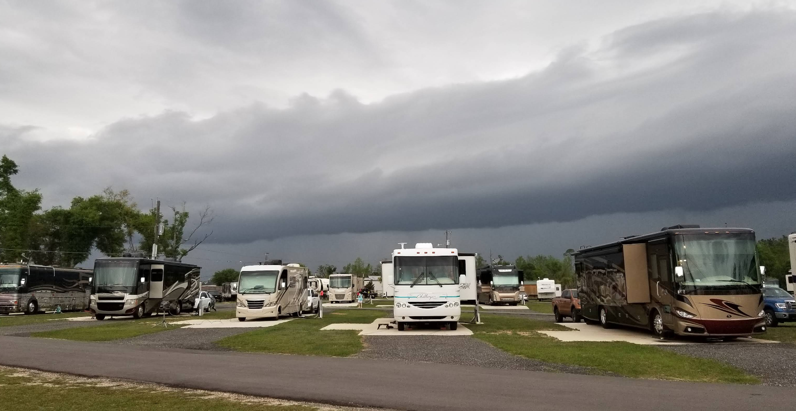 Campground with RVs parked on grass pads under a dark, stormy sky.