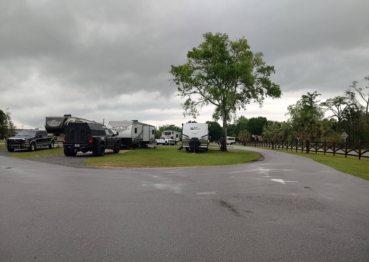 Campground with RVs and trucks on a cloudy day.