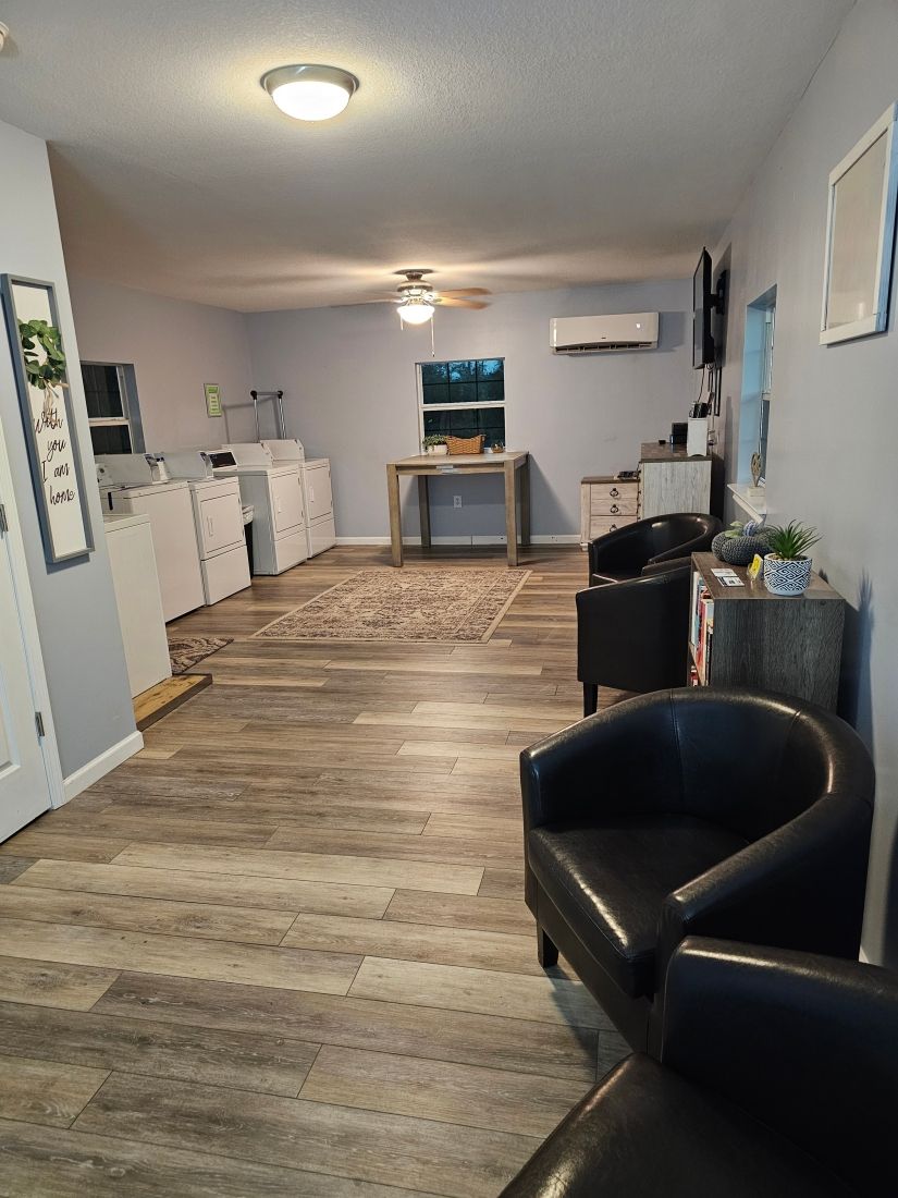 A laundromat interior with washers, dryers, seating, and a small table.