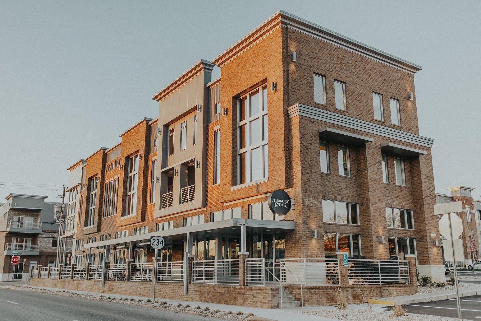 Brick building with awnings over outdoor seating; overcast sky.