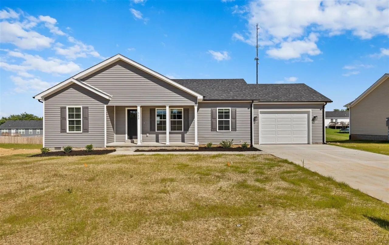 Brick house with red shutters, dormers, and a central door. Green lawn and fall trees in the yard.