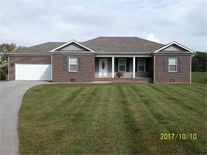 Brick ranch-style house with a white garage door and a well-manicured lawn.