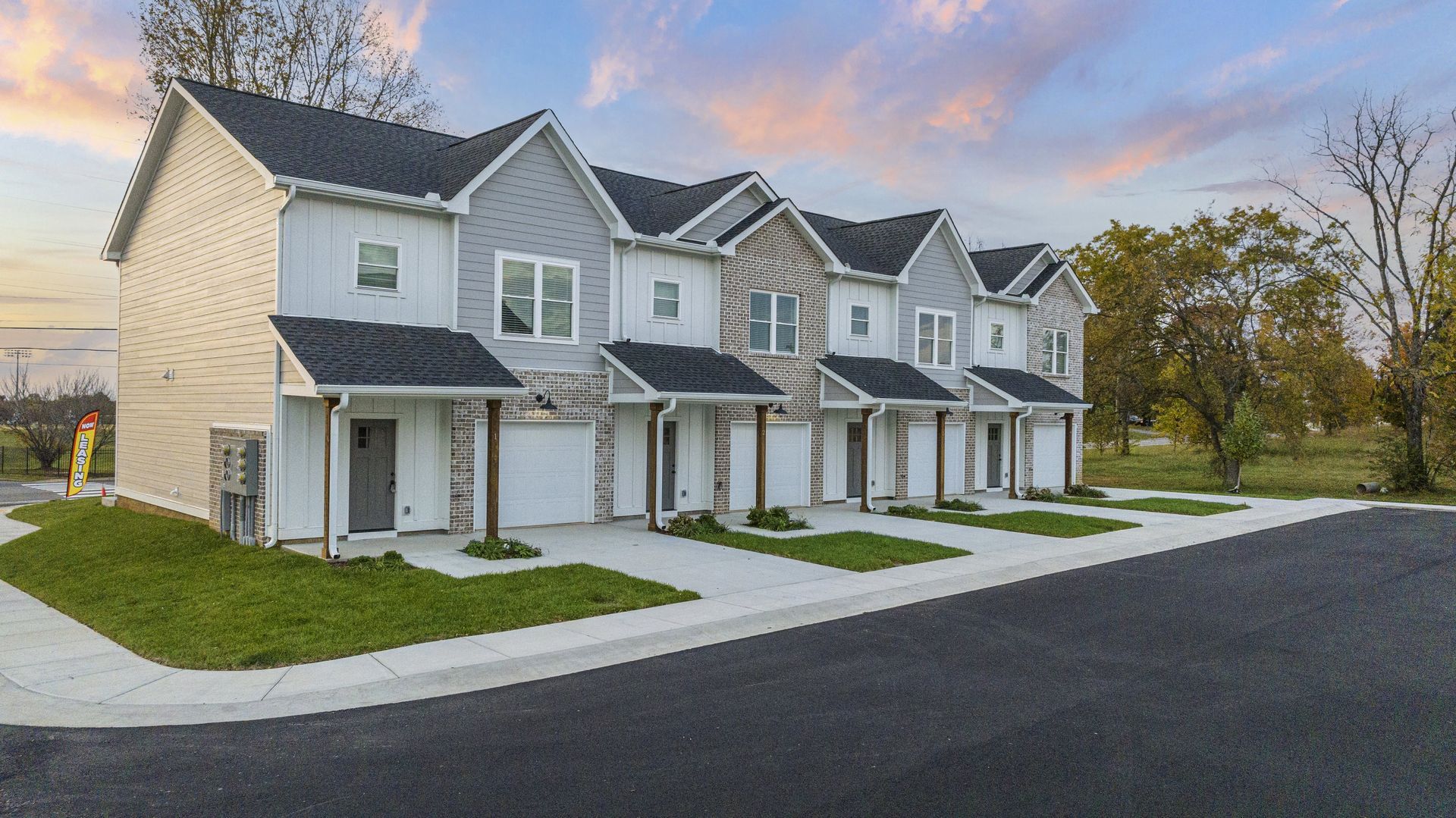 Row of modern townhouses with gray and white siding, black roofs, and attached garages.