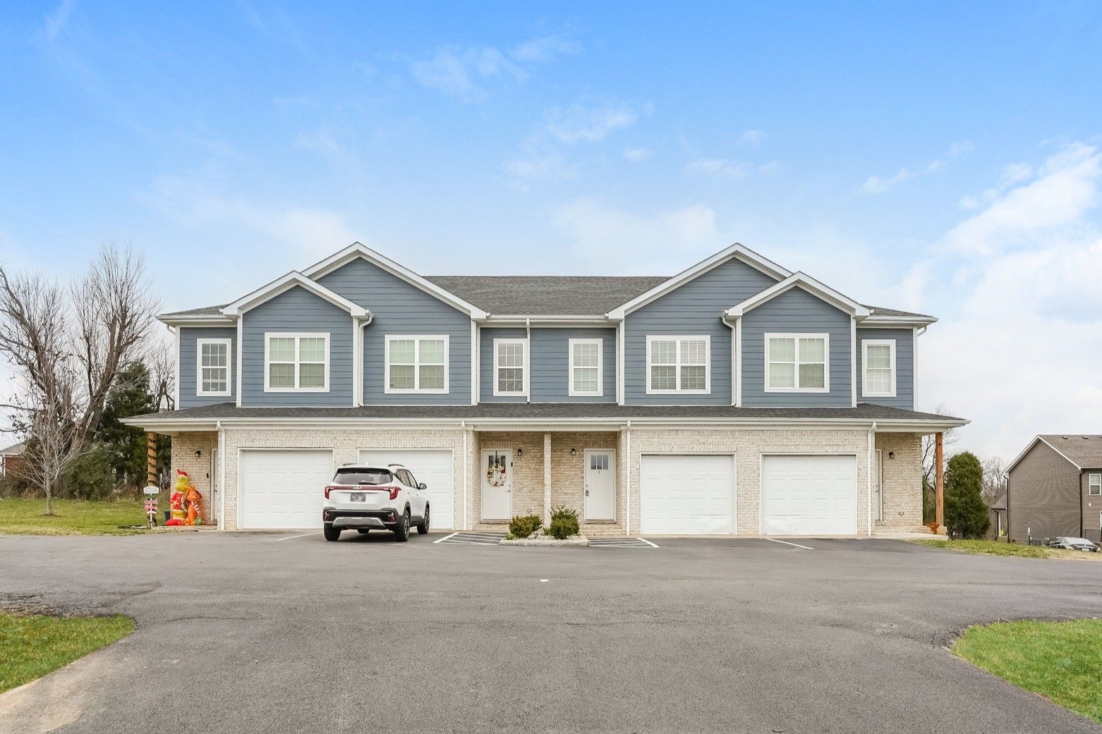 Two-story brick and white duplex with garages. White SUV parked in front of the right unit.