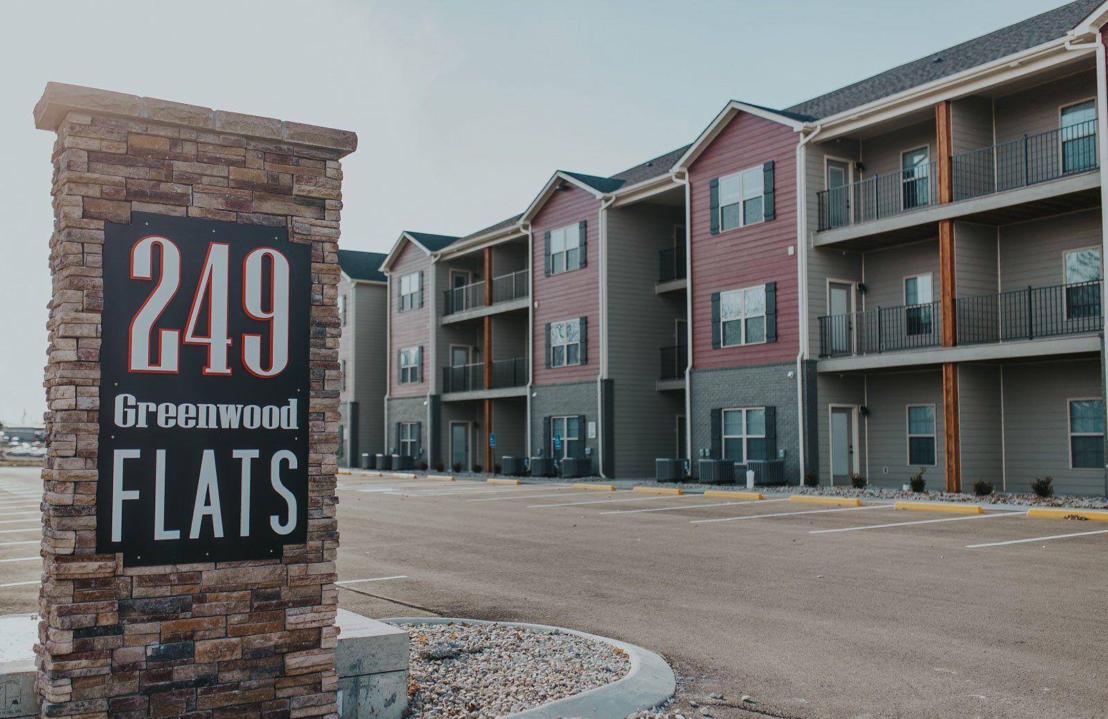 Sign for Greenwood Flats apartment complex with building in background.