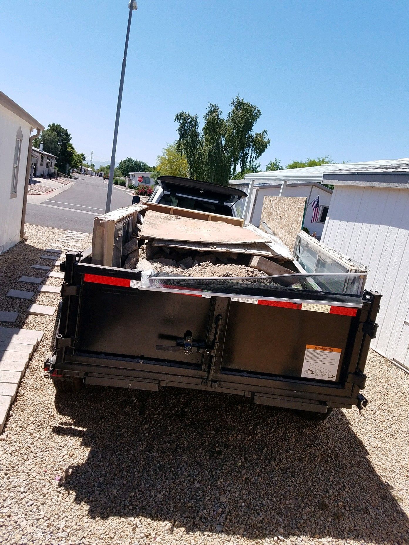 A Dumpster is Parked on the Side of the Road Next to a House