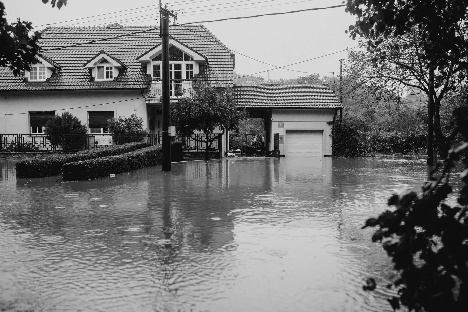 Flooded residential street with houses partially surrounded by high water.