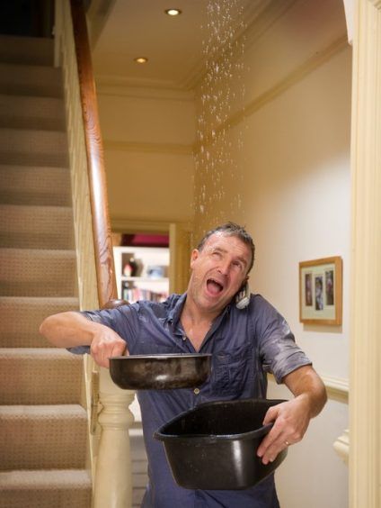 Person carrying a pot and pan up a staircase, looking startled in a hallway.