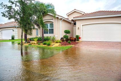 Flooded suburban house with water covering the driveway and lawn after heavy rain