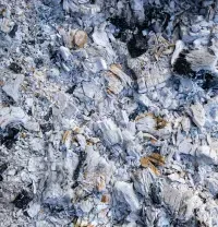 Close-up of gray and white rocky texture with scattered dark and rust-colored specks