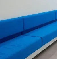 Long blue upholstered bench seating along a white wall in a modern interior
