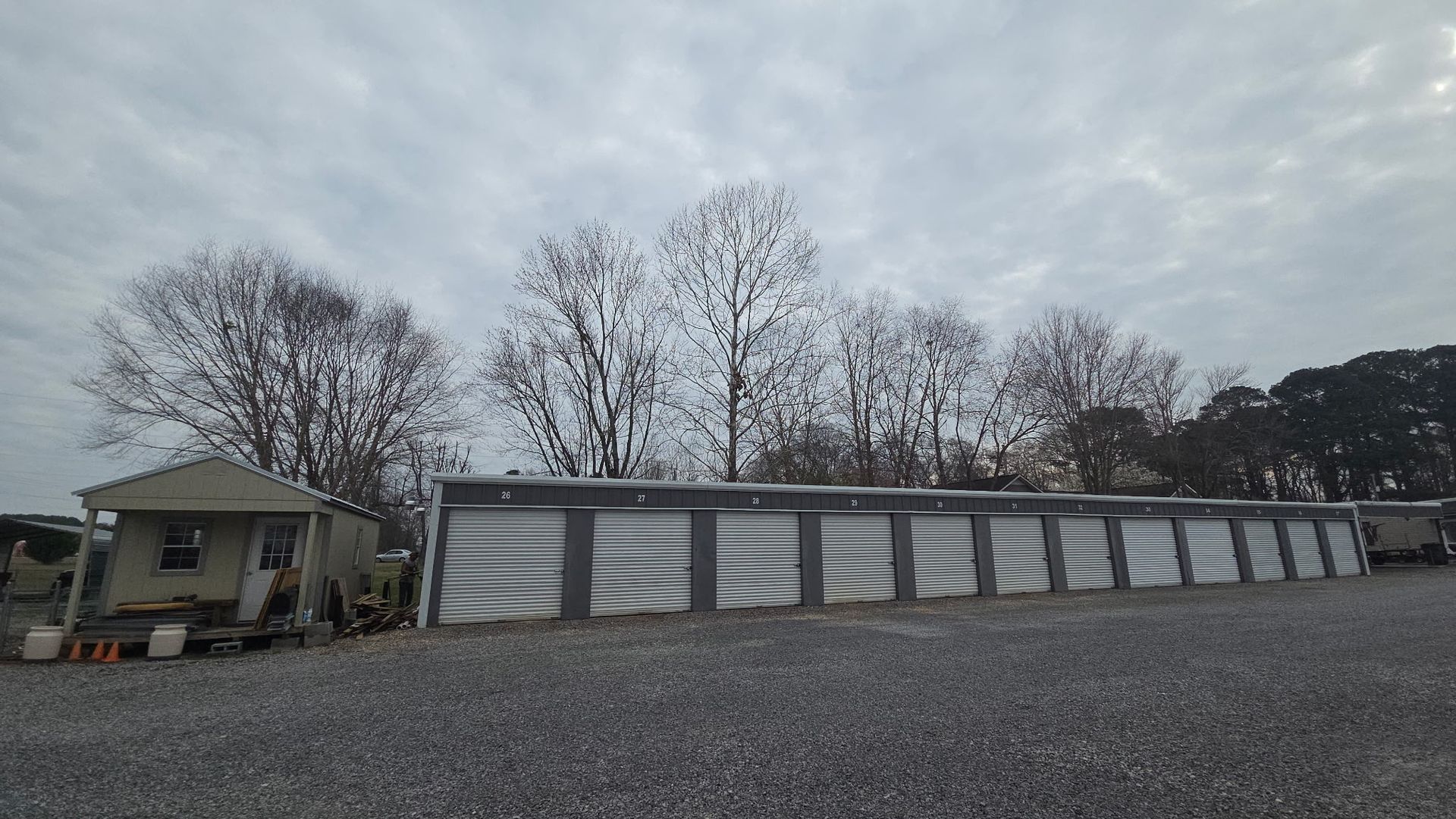 Row of gray storage units beside a small office building under a cloudy sky