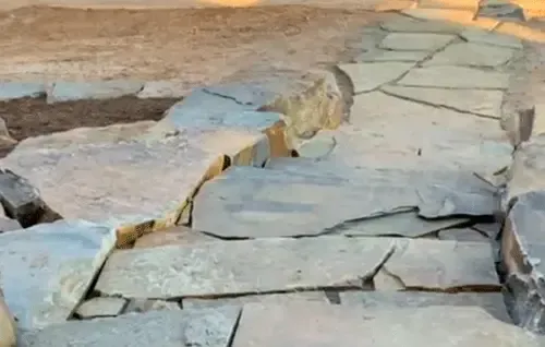 Uneven stone walkway with cracked flagstones and gaps in a rustic outdoor setting